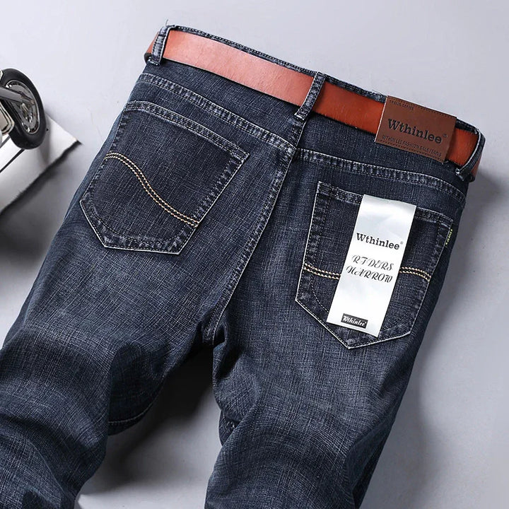 back view of dark blue denim jeans with brown belt and Wthinlee brand label on pocket