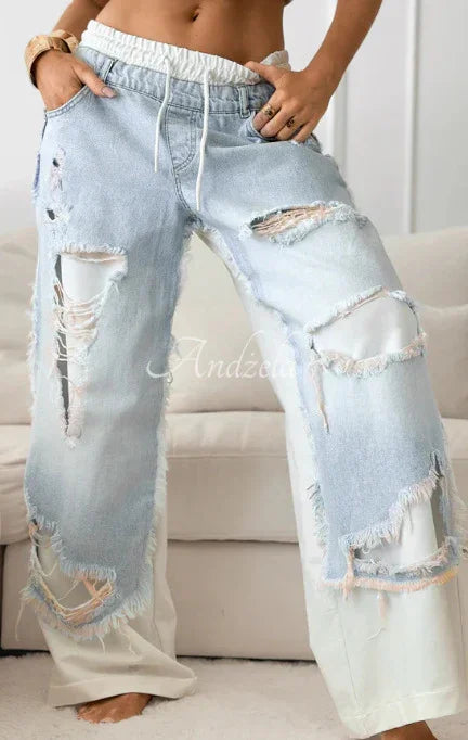 Woman wearing light blue distressed wide-leg jeans with white drawstring waist and frayed holes