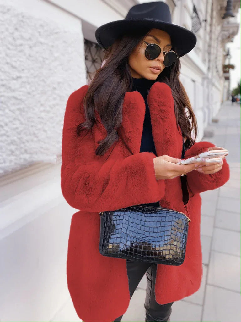 Woman wearing a red faux fur coat, black hat, round sunglasses, and carrying a black crocodile-texture handbag on city street