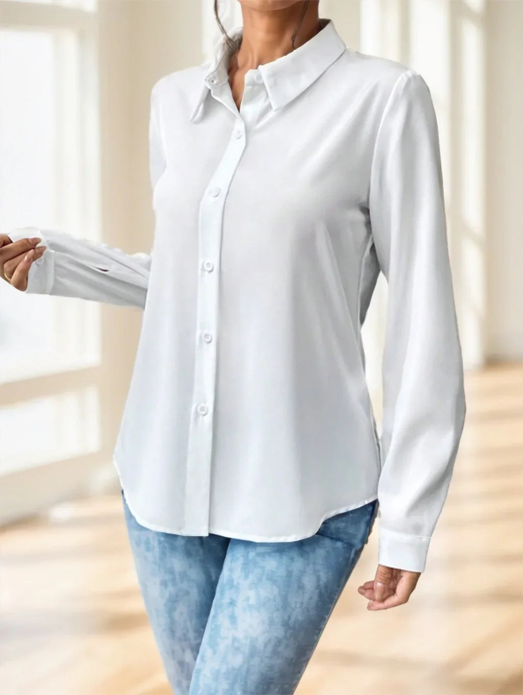 Woman wearing a white button-up shirt paired with light blue jeans in a bright indoor setting