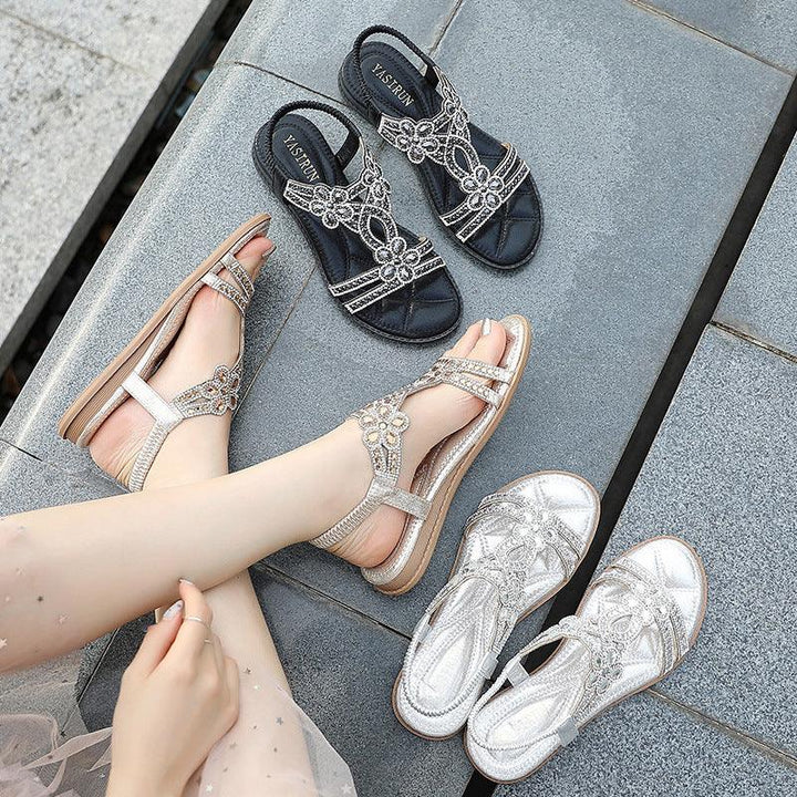 Women’s embellished sandals in black, silver, and gold on tiled pavement with model wearing gold pair