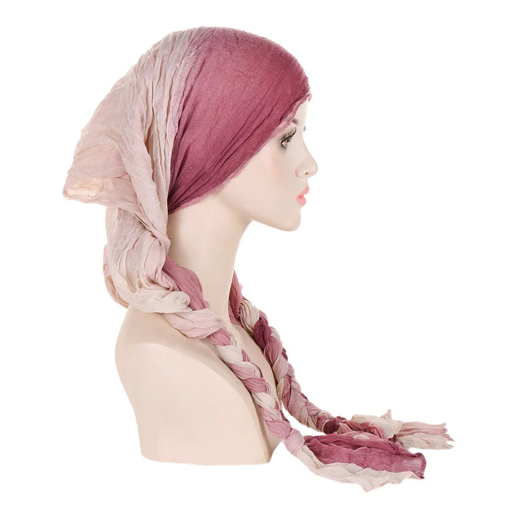Side view of mannequin head wearing pink and beige braided scarf headwrap on white background