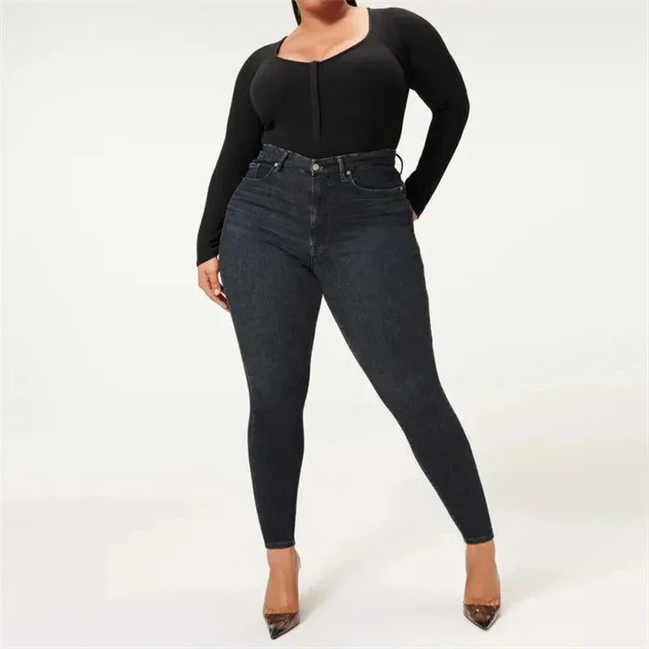 Plus size woman modeling high-waisted dark skinny jeans with black long sleeve top and heels