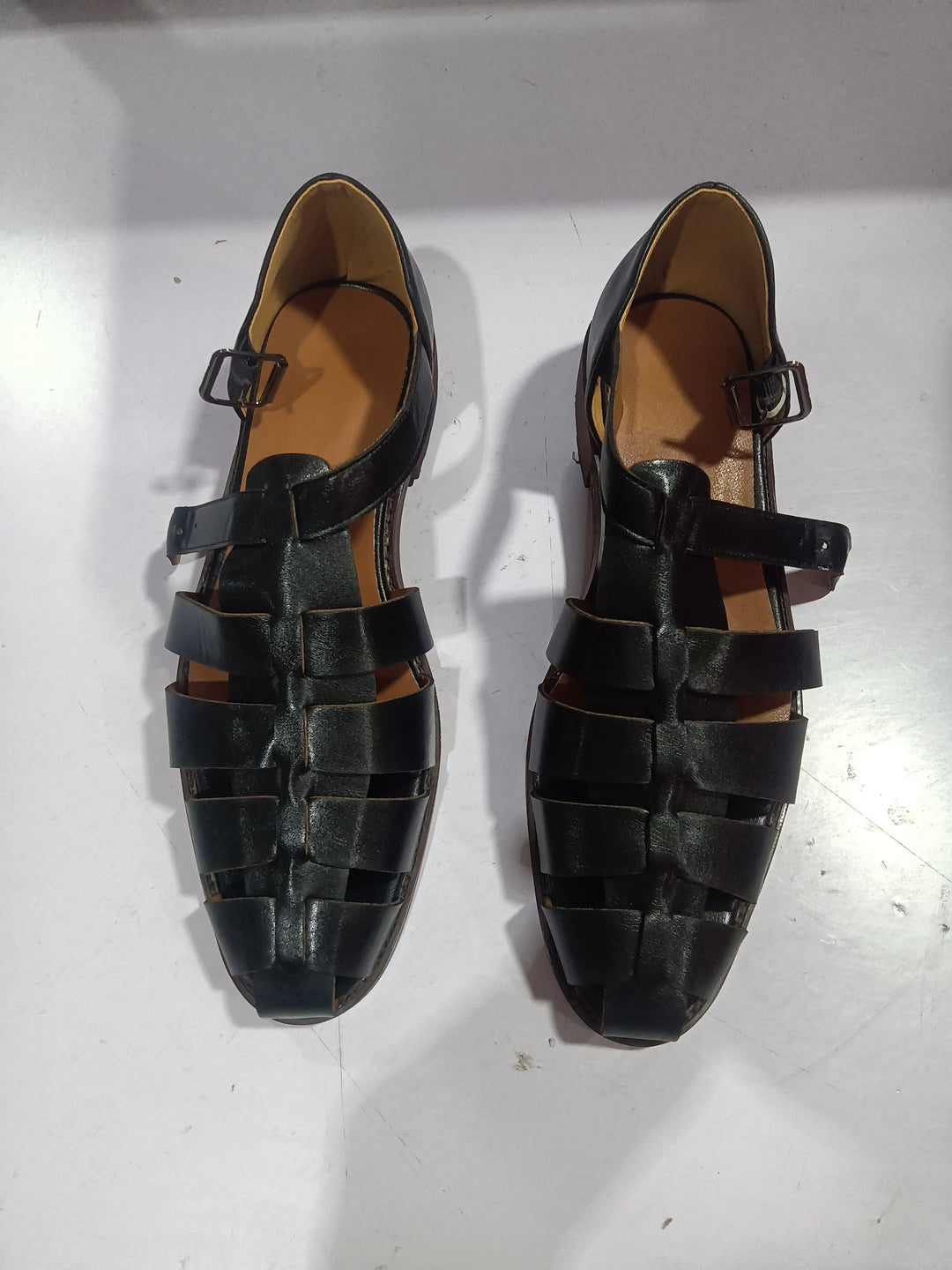 Pair of black leather men’s sandals with buckle straps on white background