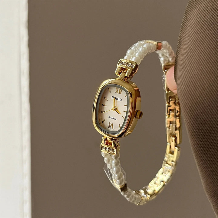 Elegant gold wristwatch with pearl and rhinestone bracelet band, white face with Roman numerals