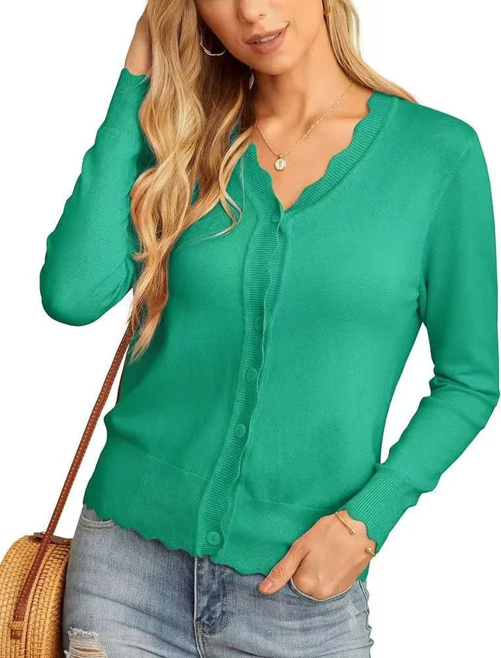 Woman wearing teal scalloped edge cardigan with buttons, paired with light wash jeans and a woven bag