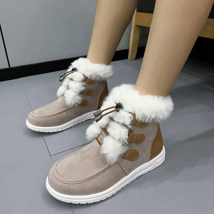 Beige winter boots with white fur trim and lace-up design on gray tiled floor