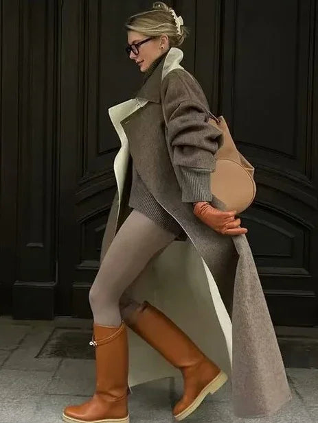 Woman walking in stylish layered fall outfit with long coat, orange gloves, brown boots, and tan bag