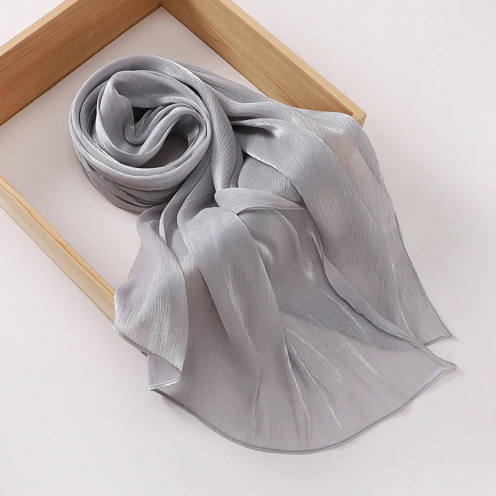 Elegant silver-gray shiny chiffon scarf rolled inside a wooden frame on a white background