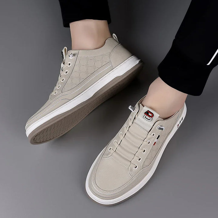 Beige casual sneakers with textured design and white soles worn with black pants