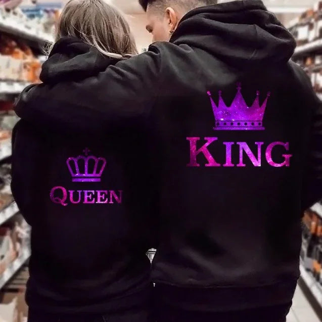 Couple wearing matching black hoodies with purple glitter King and Queen crowns in aisle