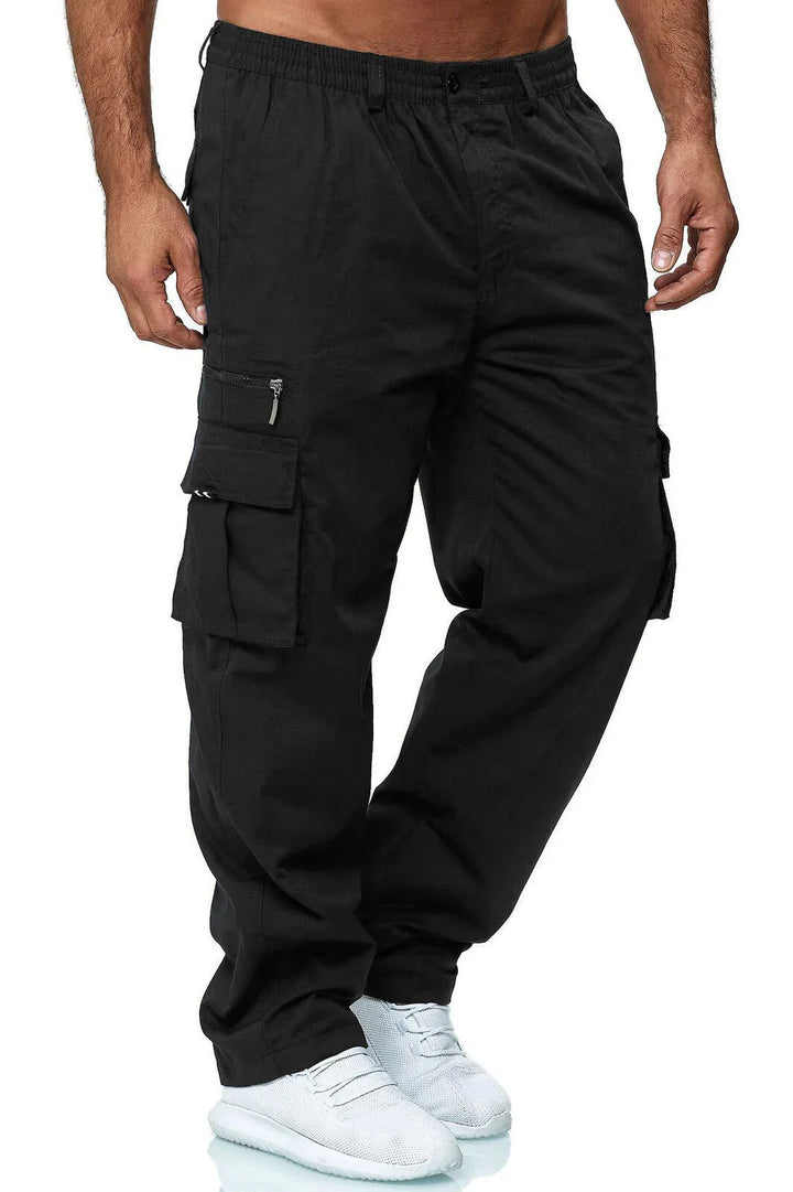 man wearing black cargo pants with side pockets and white sneakers on white background