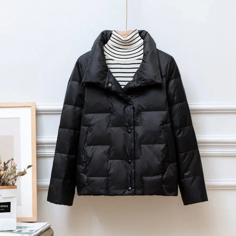 Black quilted puffer jacket with wide collar on striped turtleneck, hanging against white wall