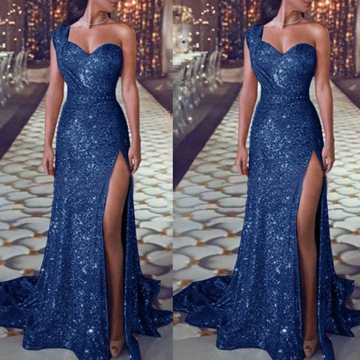 Woman wearing a sparkling navy blue one-shoulder evening gown with thigh-high slit on patterned floor