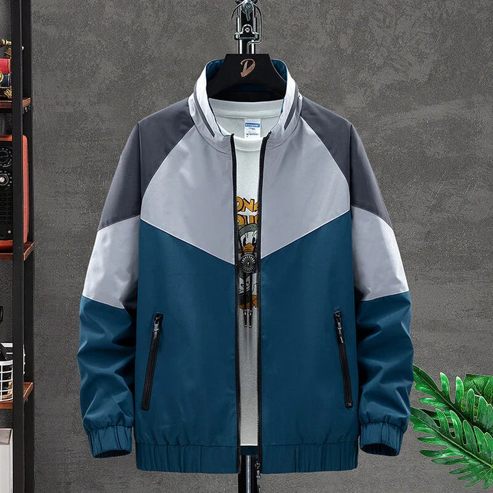 Men's colorblock zip jacket in blue, gray, and white on black hanger against gray wall