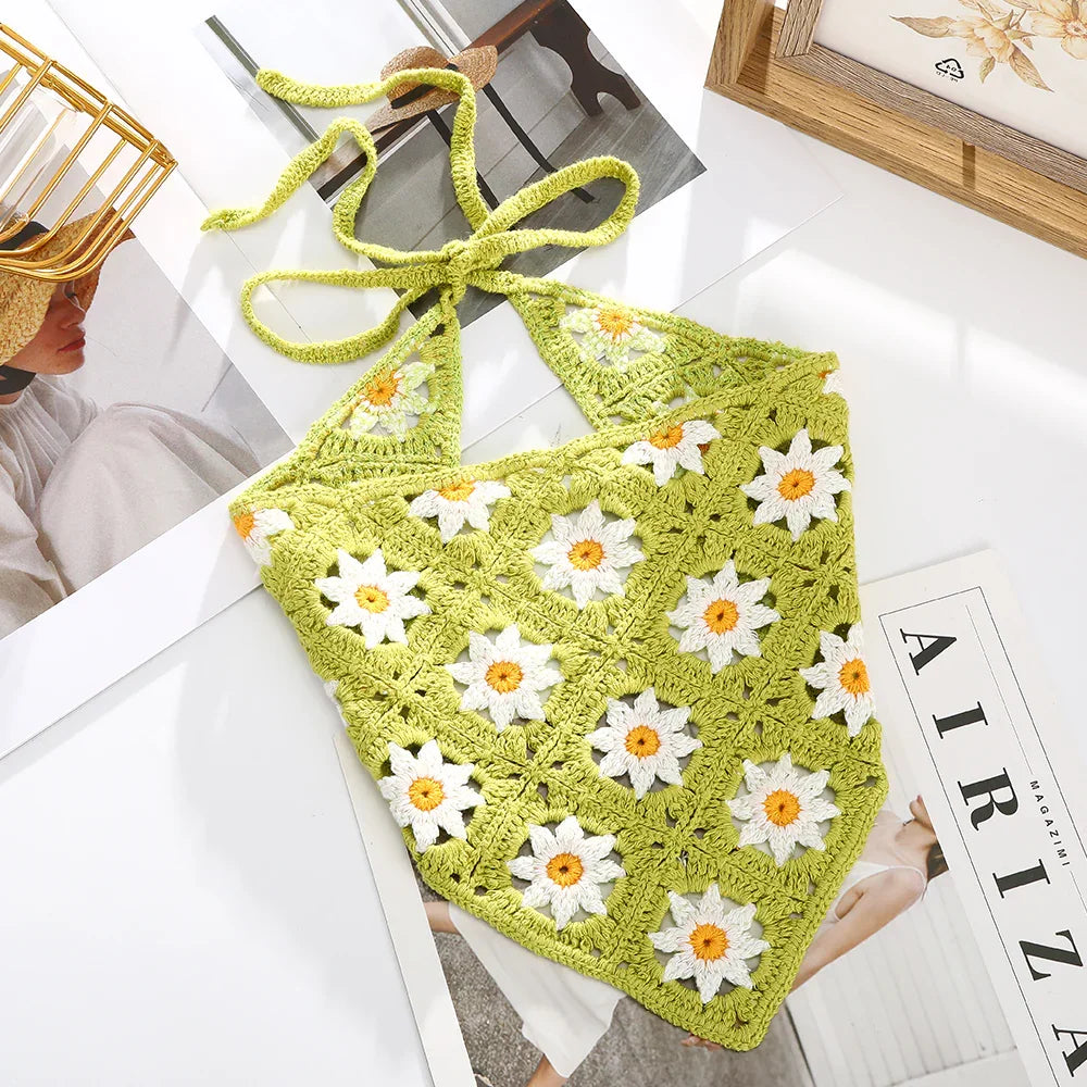 Green crochet halter top with white and yellow daisy patterns on a white surface