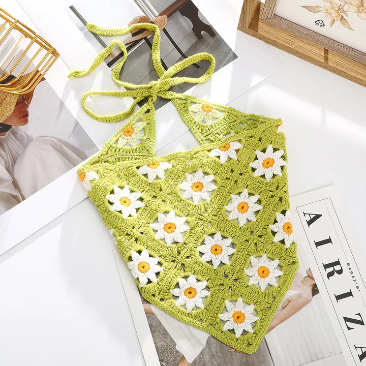 Green crochet halter top with white and yellow daisy patterns on a white surface