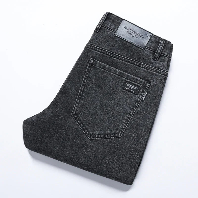 Folded black denim jeans with back pocket and Fashion Jeans leather label on white background