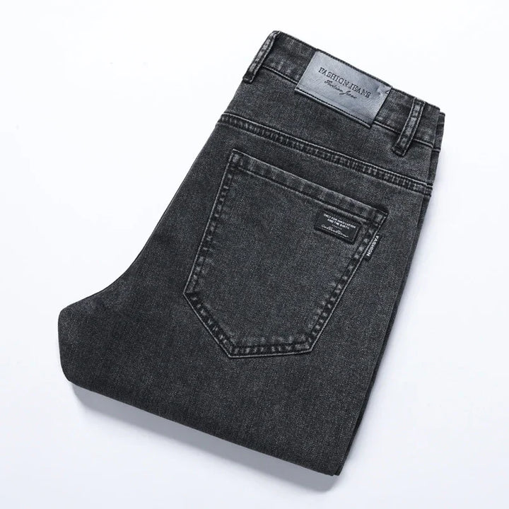 Folded black denim jeans with back pocket and Fashion Jeans leather label on white background
