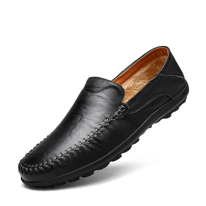 Black leather moccasin slipper with fur lining and stitched detailing on white background
