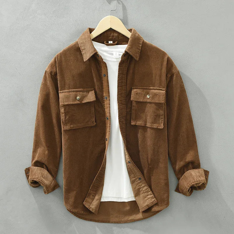 Brown corduroy overshirt with buttoned flap pockets, layered over a white t-shirt on hanger