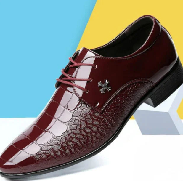 Burgundy men's formal leather shoe with crocodile texture and lace-up design on geometric background