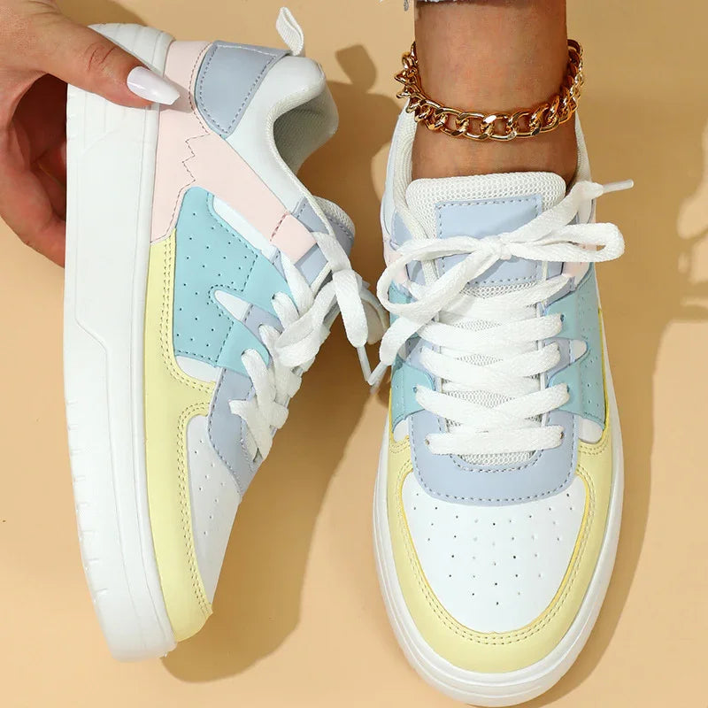 Pair of pastel colorblock sneakers in white, light blue, yellow, and pink with white laces on beige background