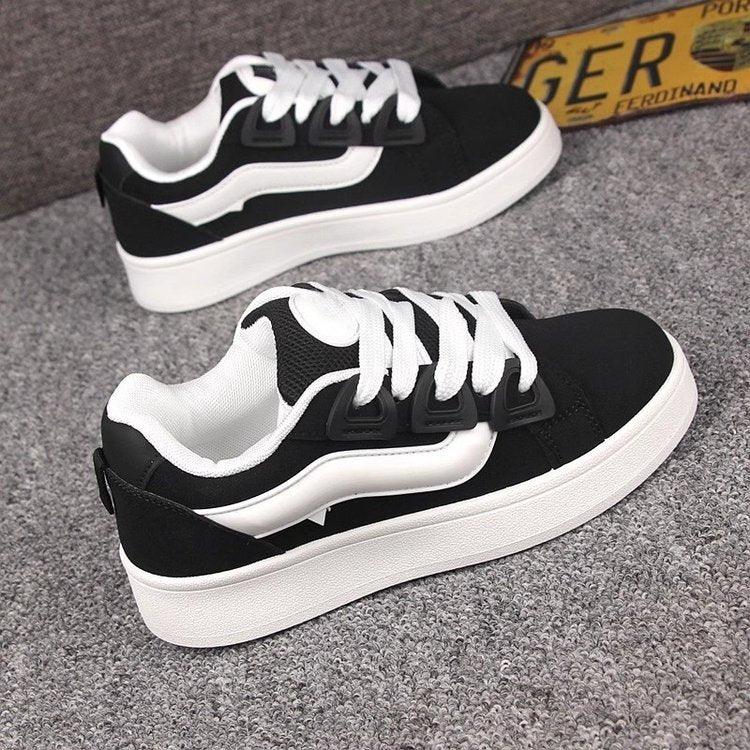 Black and white casual sneakers with thick white soles on gray carpet
