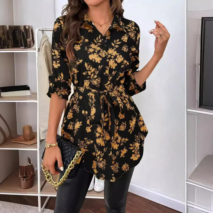 Woman wearing black floral button-up tunic with tan flower print and black leather pants