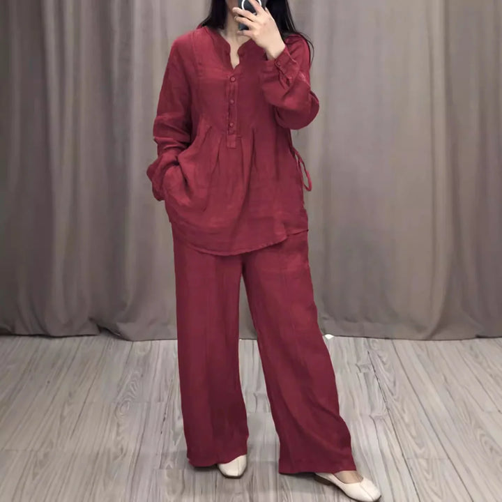 Woman wearing a loose red long-sleeve blouse and wide-leg pants standing on wooden floor