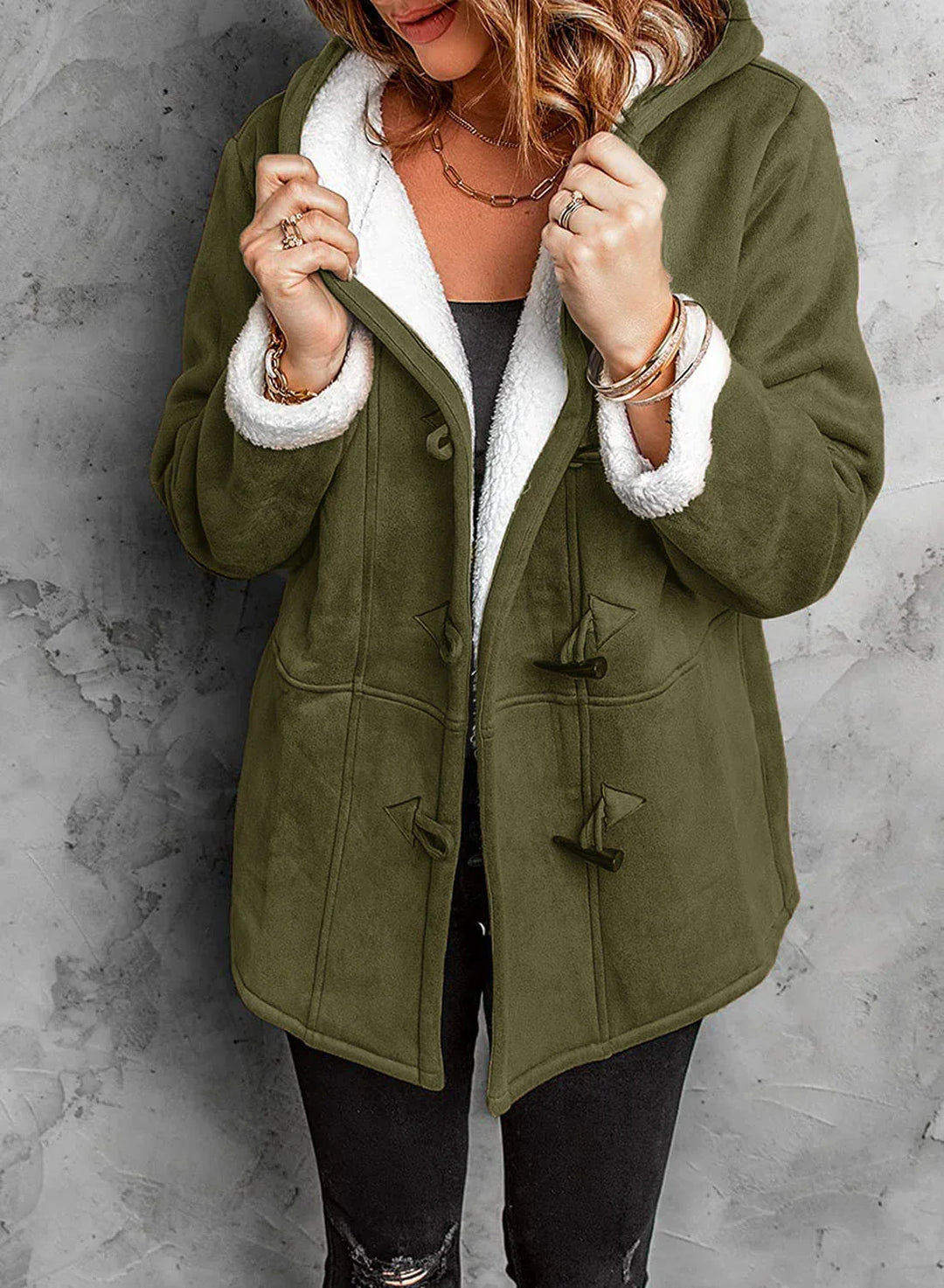 Woman wearing olive green hooded coat with white sherpa fleece lining and toggle buttons