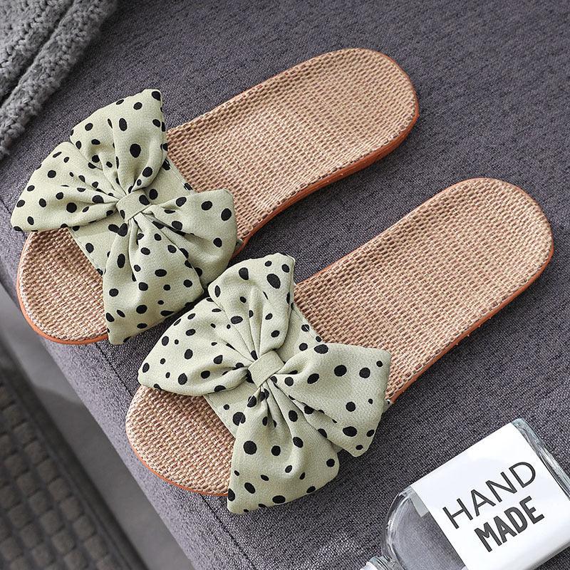 Handmade woven slide sandals with green polka dot fabric bows on gray textured surface