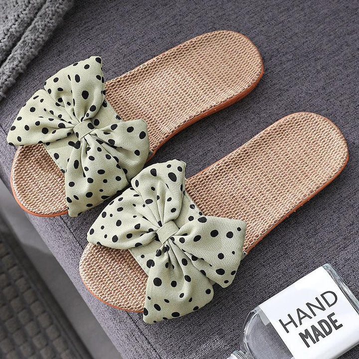 Handmade woven slide sandals with green polka dot fabric bows on gray textured surface