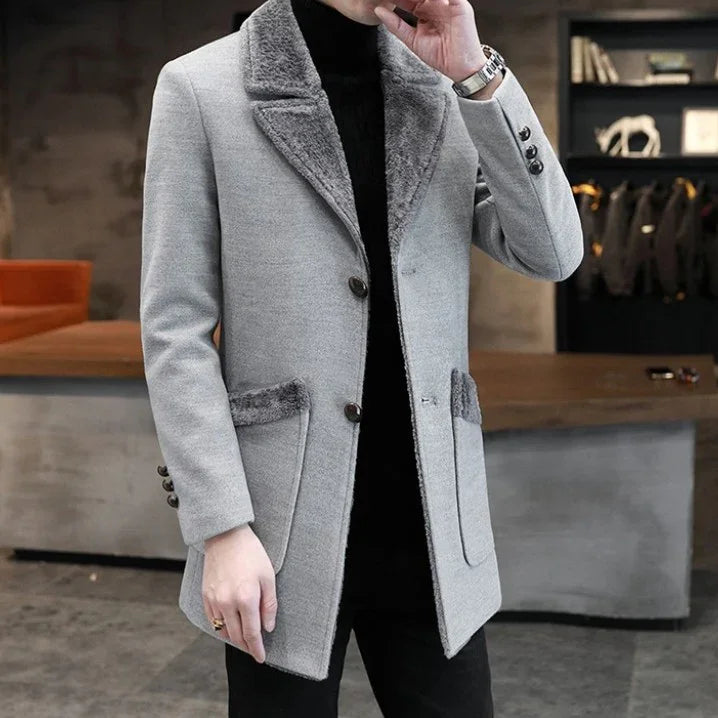 Man wearing a stylish grey wool coat with fur collar and pockets, indoors in modern setting