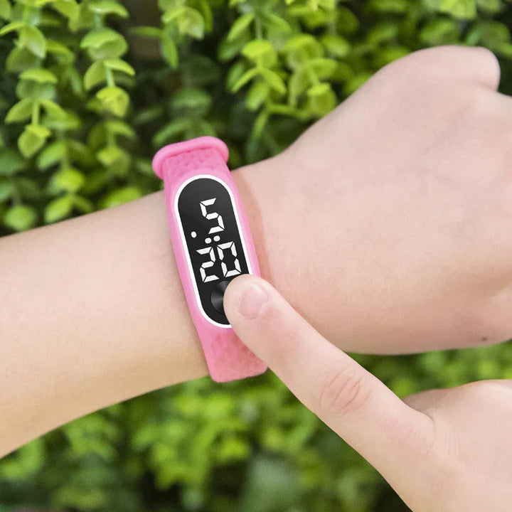 Person wearing pink digital wristwatch showing time 5:20 with finger touching screen outdoors