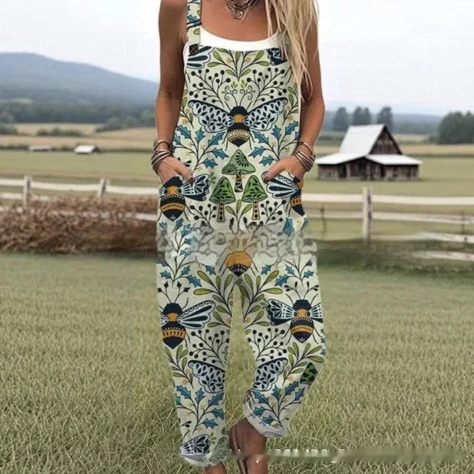 Woman wearing floral and bee patterned jumpsuit with pockets, standing in a rural field with a barn in the background