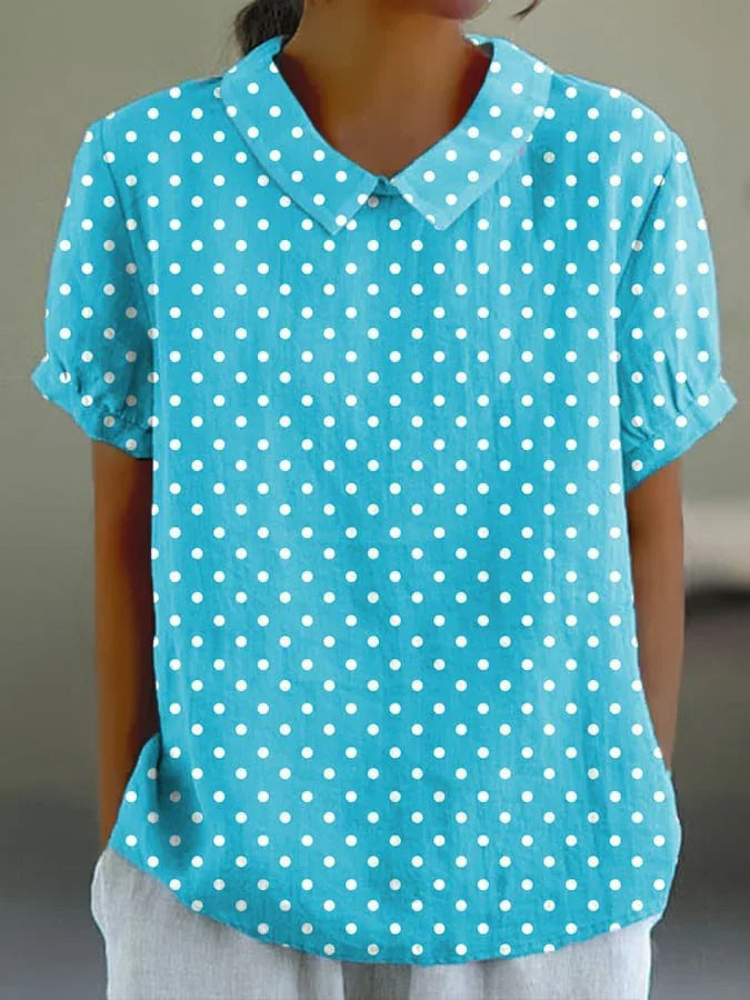 Woman wearing a blue short-sleeve collared blouse with white polka dots, casual style