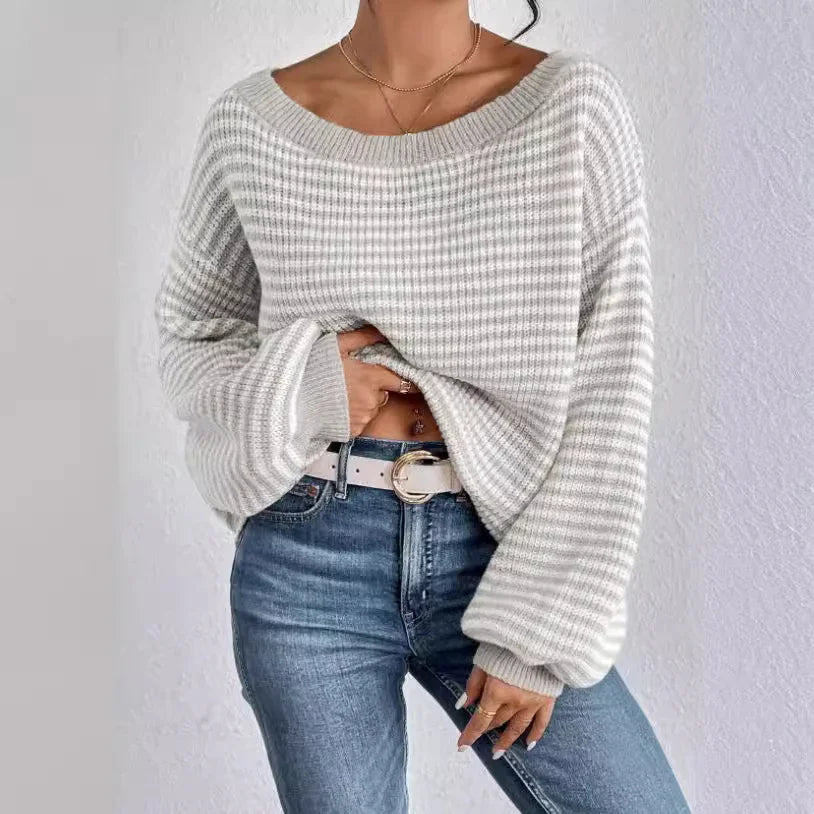 Woman wearing a cozy gray and white striped knit sweater with balloon sleeves and blue jeans