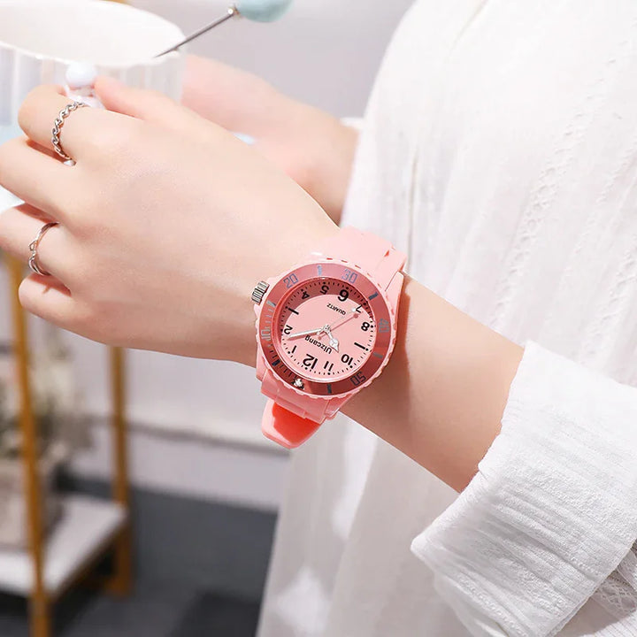 Close-up of person wearing pink silicone wristwatch with numeric dial and silver rings on fingers