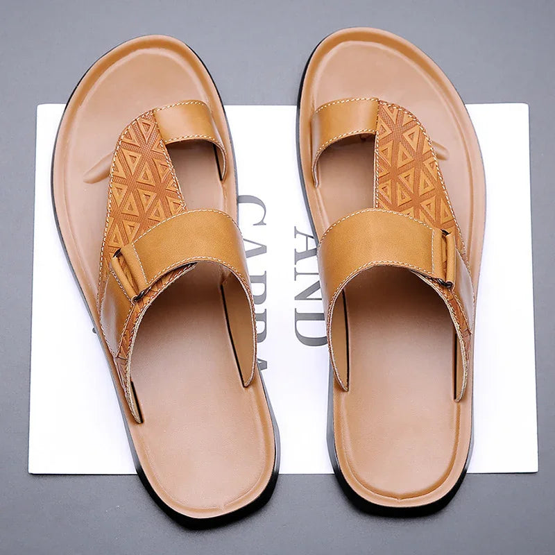 Men's tan leather slip-on sandals with geometric pattern and adjustable strap on gray background