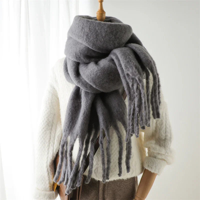 Cozy thick gray wool scarf with fringes on a mannequin wearing a white knit sweater