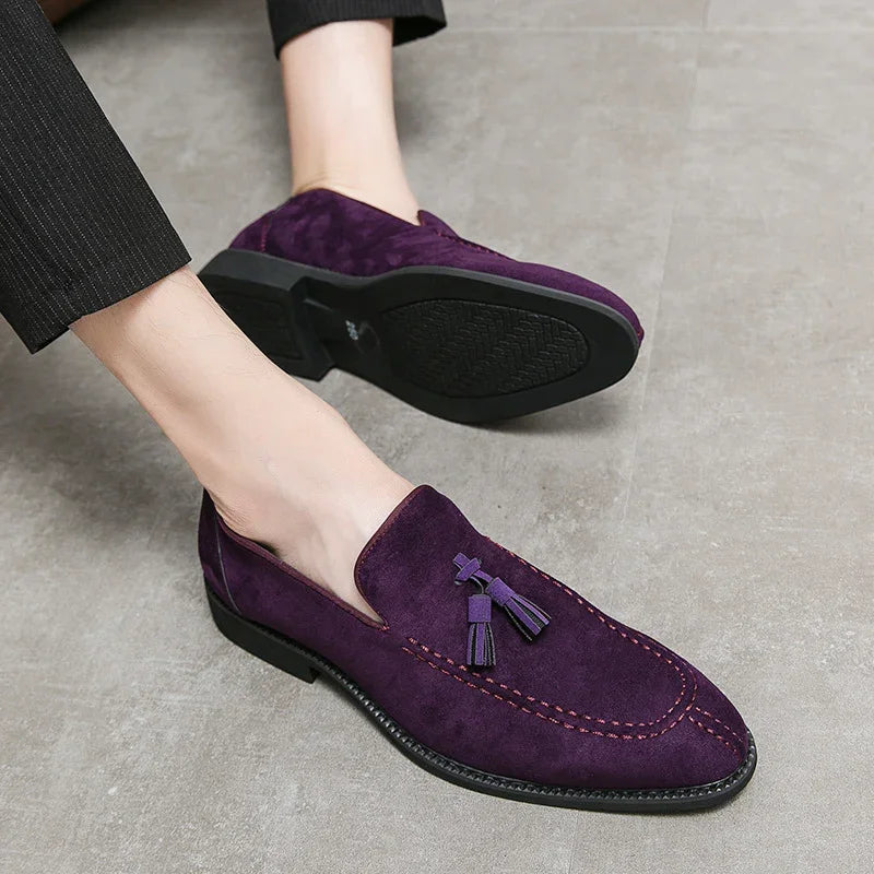 Men's purple suede tassel loafers with black soles worn with black pants on gray floor