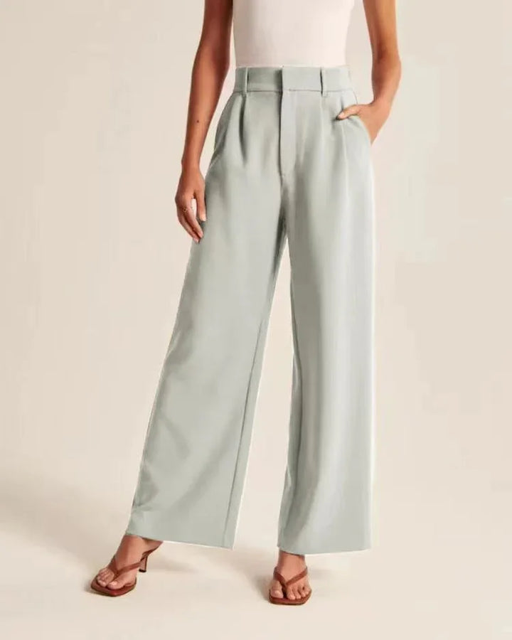 Woman wearing light gray high-waisted wide-leg pants with front pleats and pockets