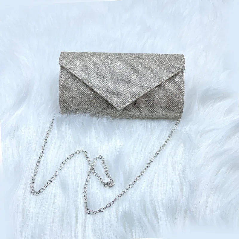 silver glitter clutch bag with chain strap on white faux fur background