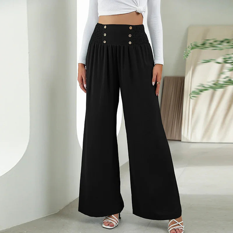 Woman wearing high-waisted black wide-leg pants with button details and white strappy heels