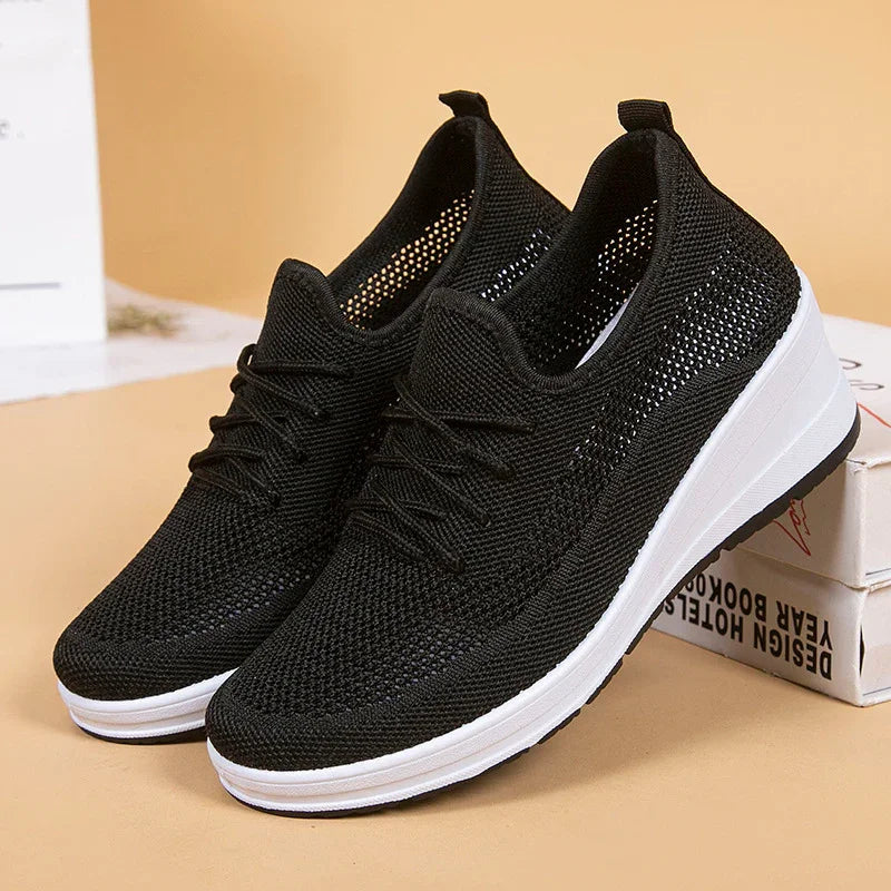 Black knit breathable sneakers with white thick sole, lightweight sports shoes on beige background