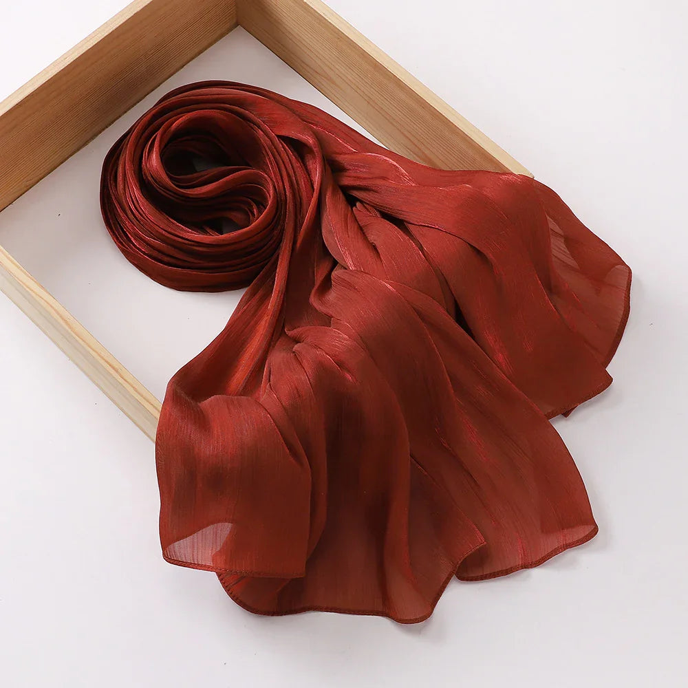 Rust red sheer chiffon scarf elegantly draped inside a wooden frame on white background