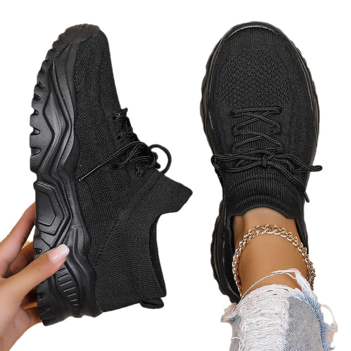 Black knitted sock sneakers with chunky soles, worn with gold chain anklet and distressed jeans
