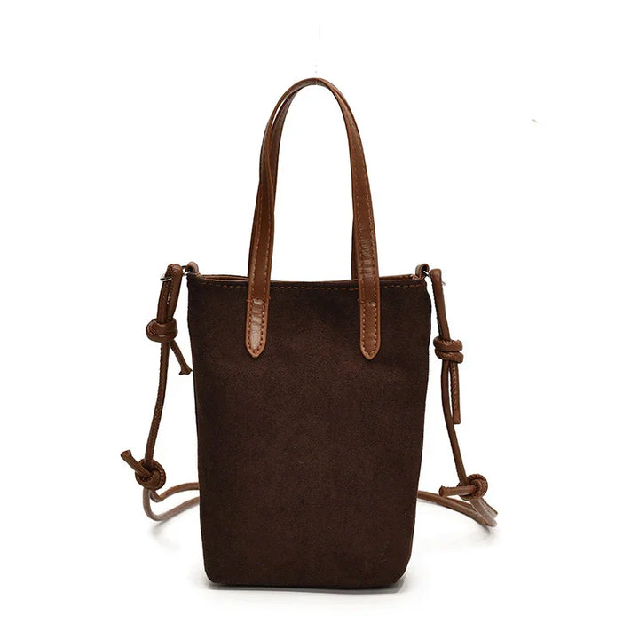 Small brown suede bucket bag with leather handles and adjustable shoulder strap on white background