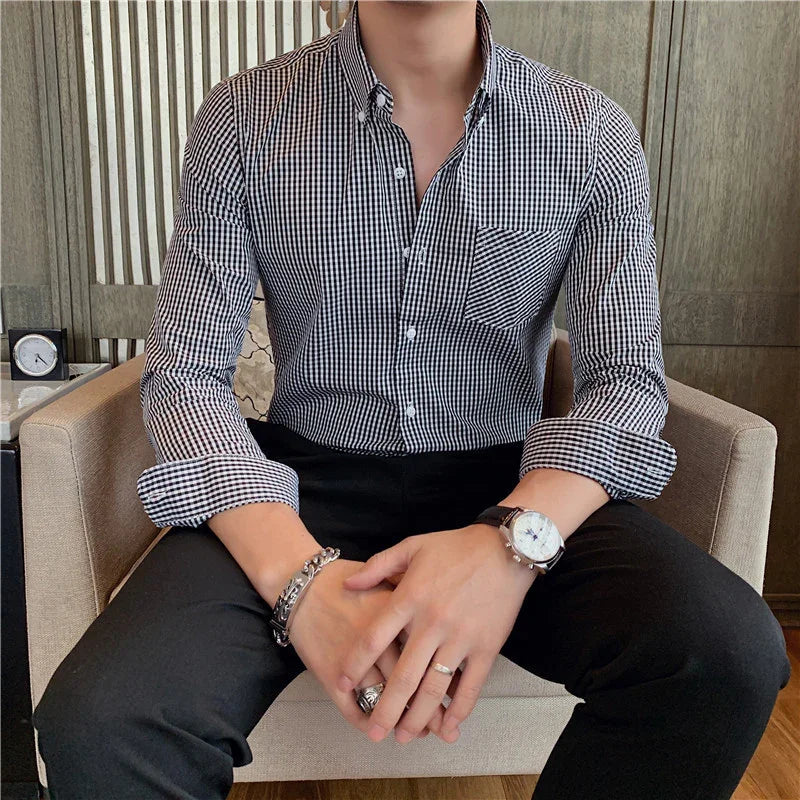 Man wearing black and white checkered dress shirt with black pants sitting on beige armchair